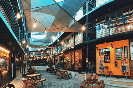 A view of The Grid food park with hanging lights and wooden tables and chairs