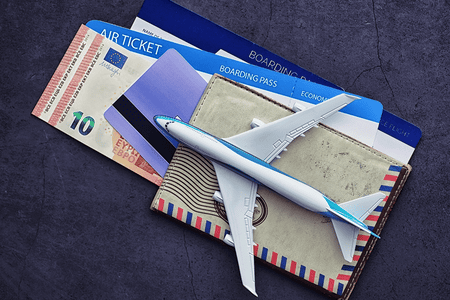 airplane model on top of a card, money, and plane tickets