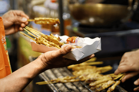 A person about to eat street food in skewers