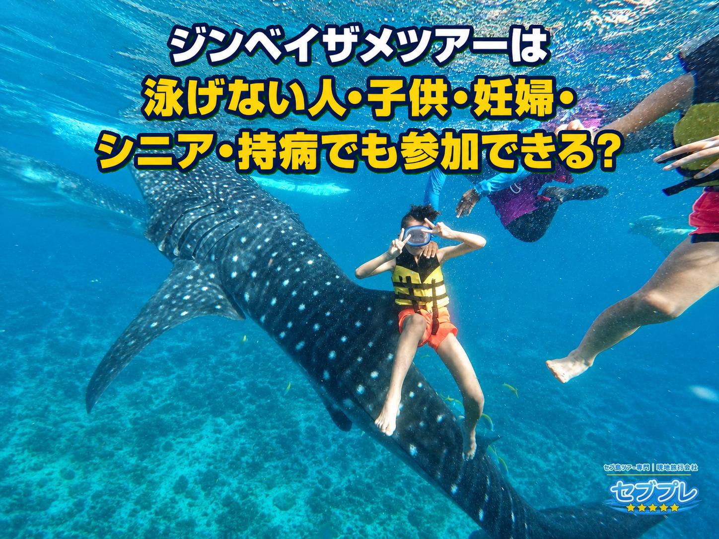 黄色いライフジャケットとゴーグルの子供がジンベイザメの近くで両手ピースをする水中実写。子供でも浮いて楽しめることを示す。
